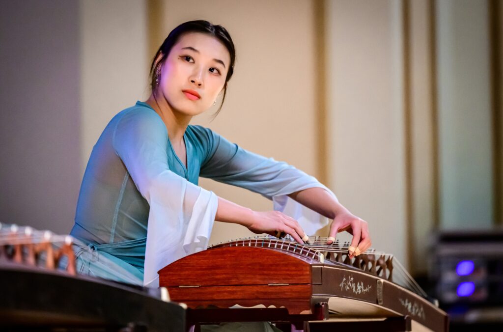 Student playing classical multistring instrument from China